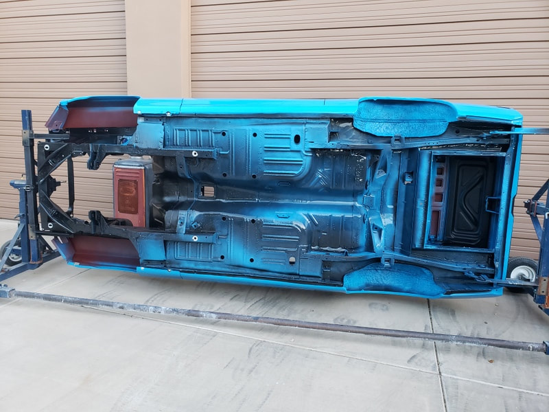 Car chassis painted bright blue, flipped on its side.