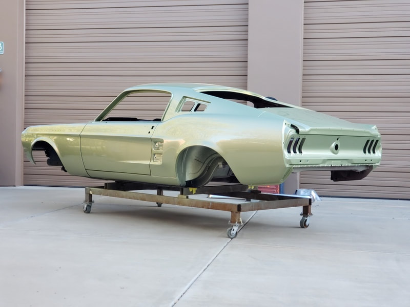 Classic Ford Mustang fastback car body on a dolly, painted light green.