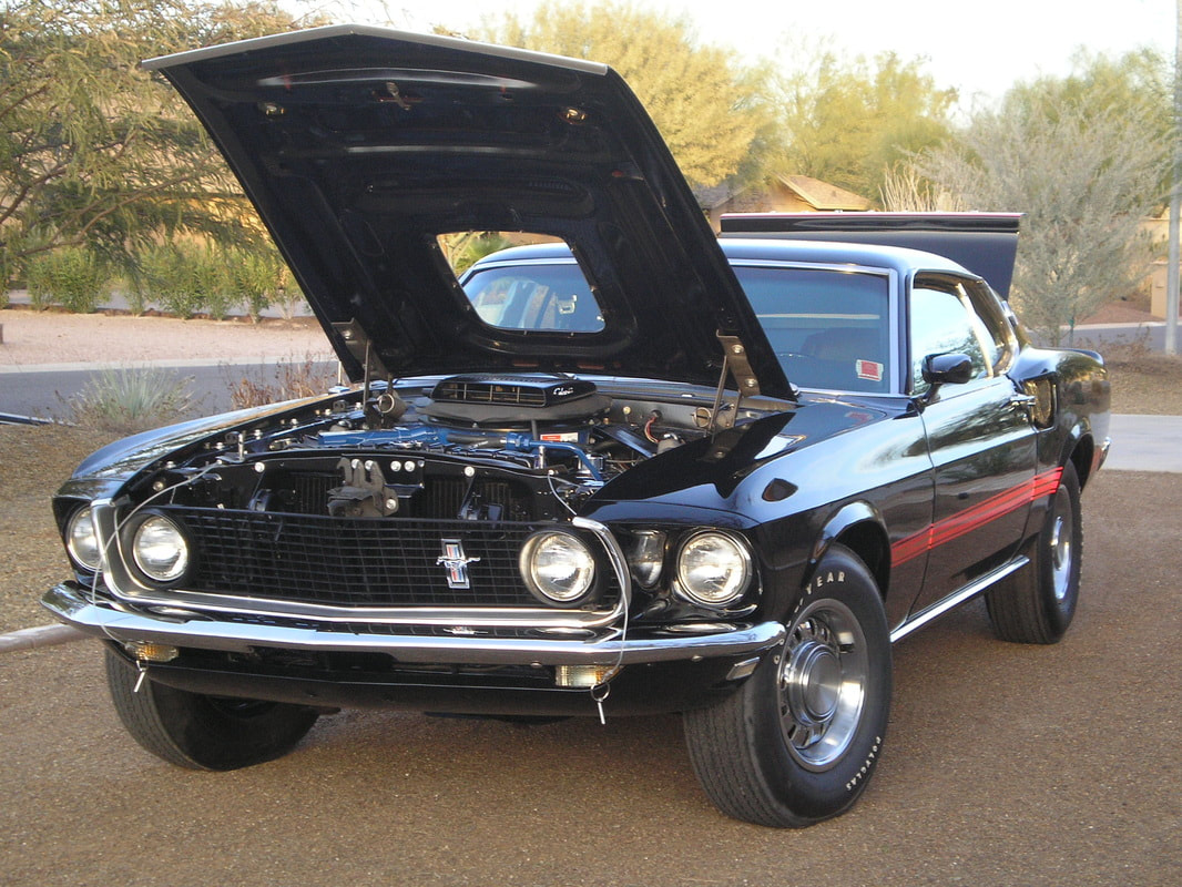 Classic black 1960s Ford Mustang with hood open.