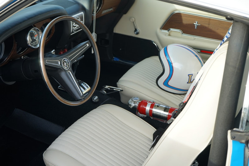 Classic car interior with white seats and a fire extinguisher.