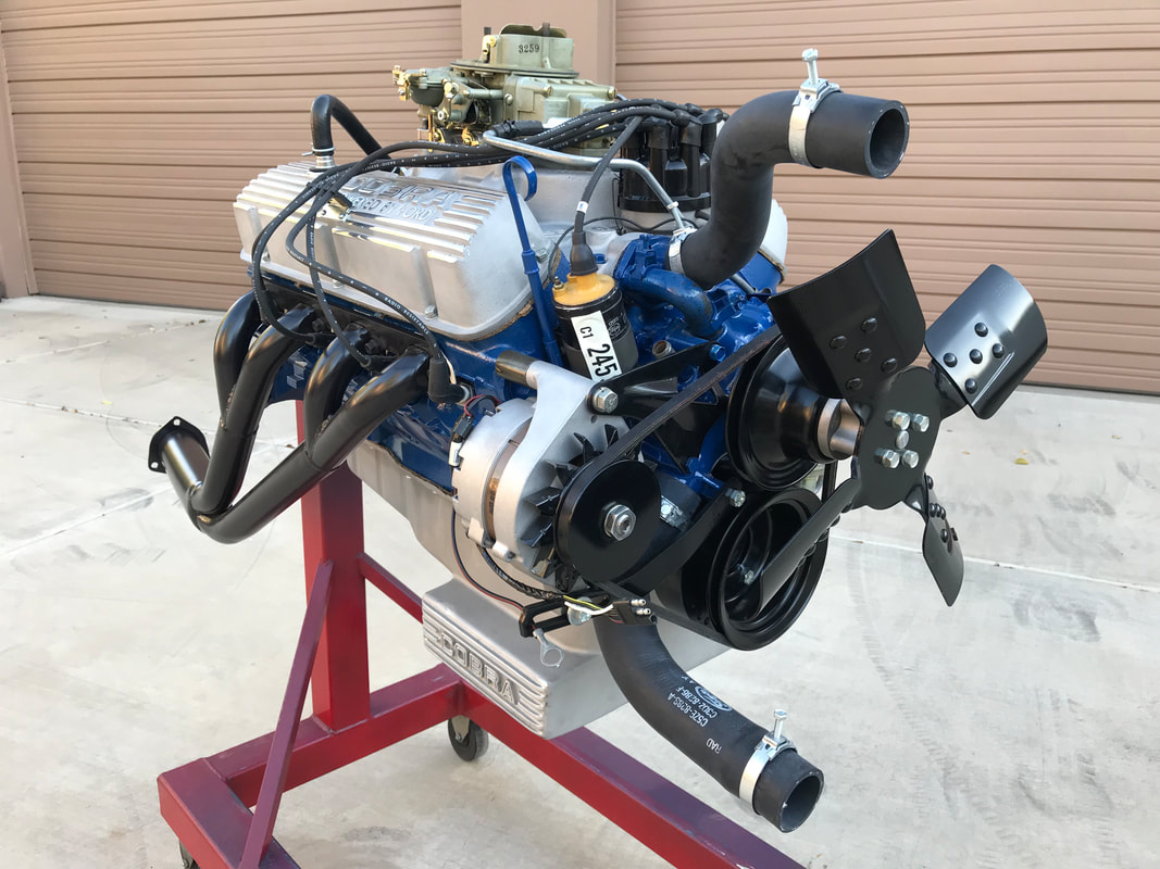 A blue vintage car engine mounted on a stand, showcasing various components.