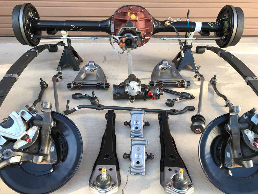 Various car suspension and drivetrain parts laid out on the floor.