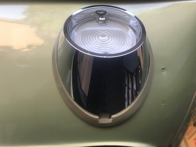 Close-up of a vintage car headlight with a protective glass cover.