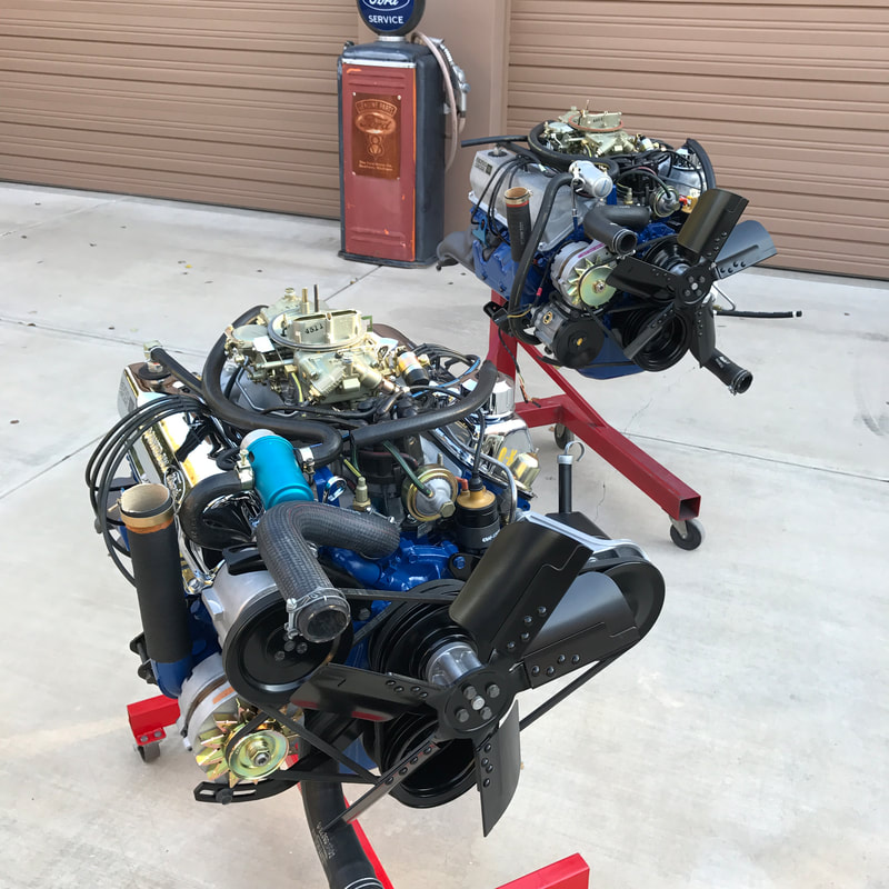 Two engines mounted on red stands outdoors on concrete.