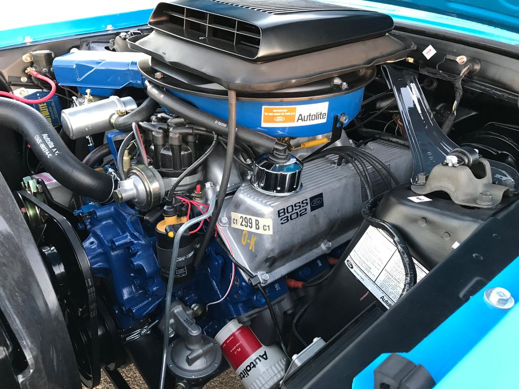 Close-up of a vintage car engine with detailed components and labels.