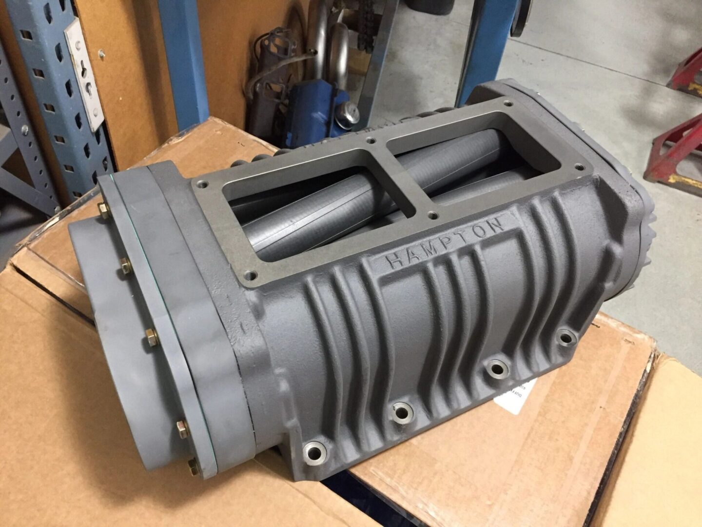 Supercharger on cardboard box in workshop.