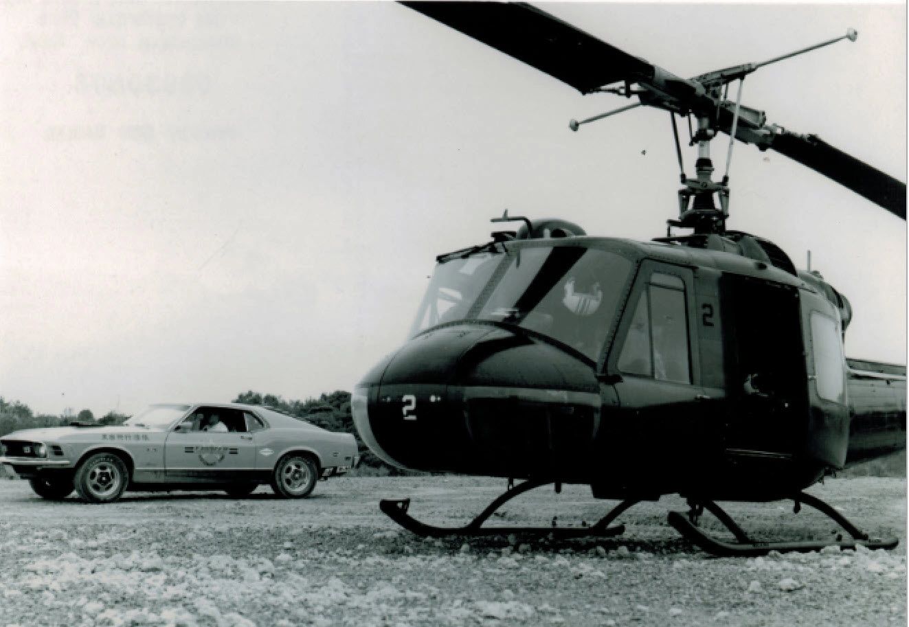Helicopter and car parked on rocky ground.