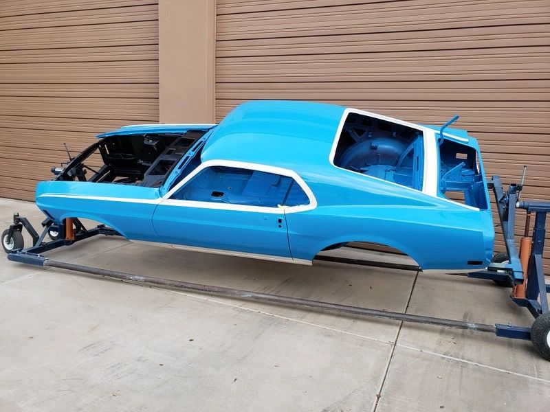 Blue car body on a rotisserie stand.