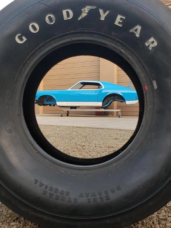 Blue car framed through large tire.