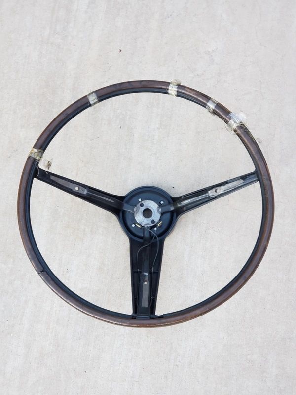 Vintage wooden car steering wheel on ground.