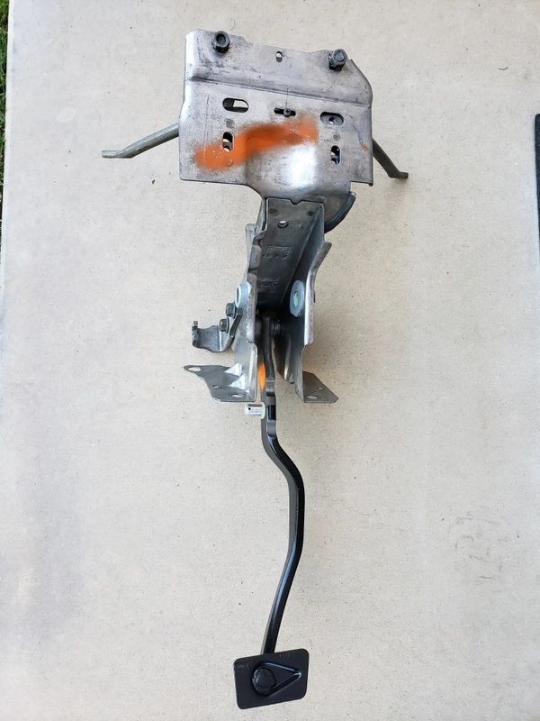 Metal car brake pedal assembly on concrete.