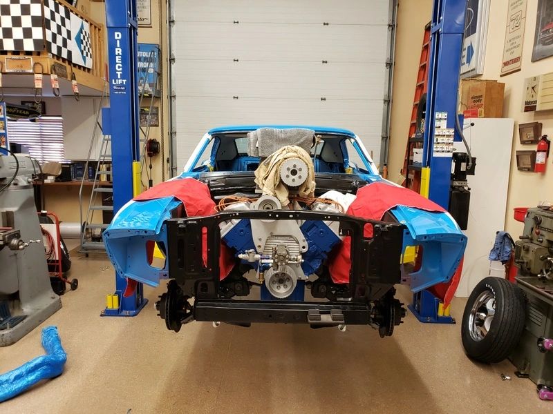 Blue car under repair in garage.