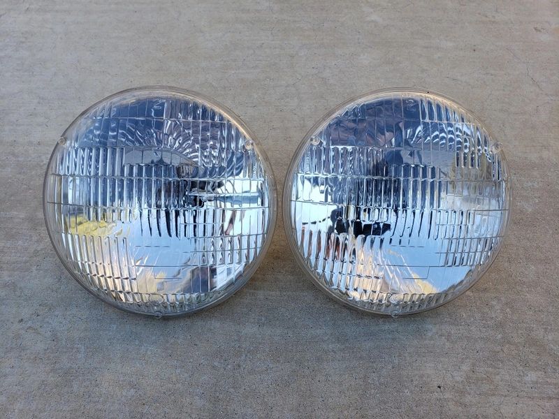 Two round car headlights on concrete surface.
