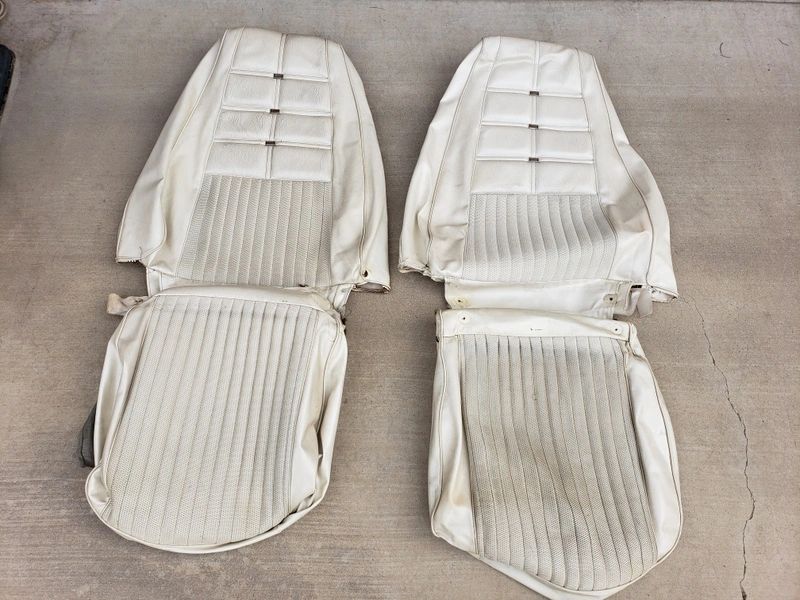 Two white car seat covers on ground.