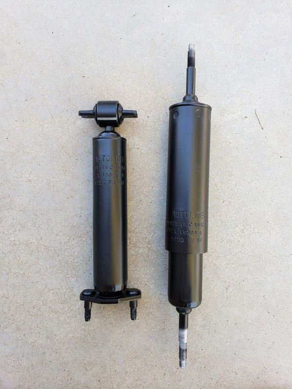 Two black shock absorbers on concrete surface.