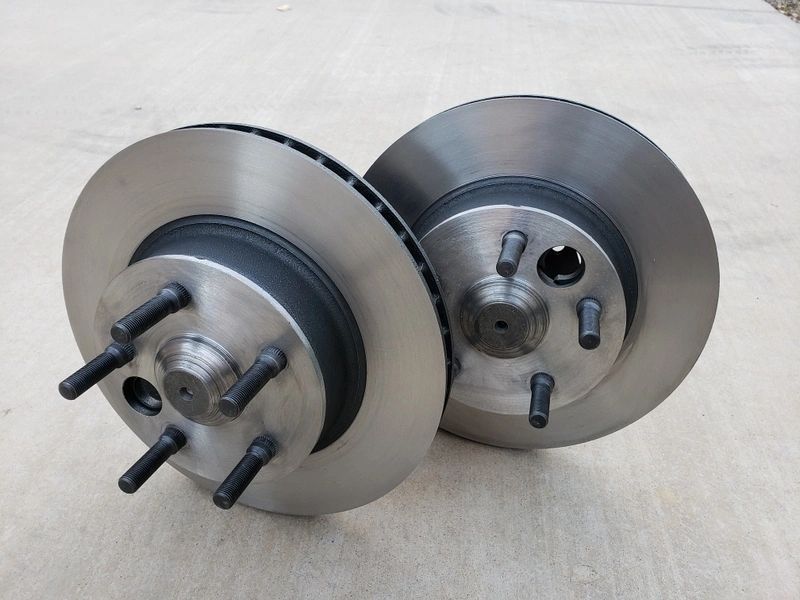 Two car brake rotors on concrete surface.
