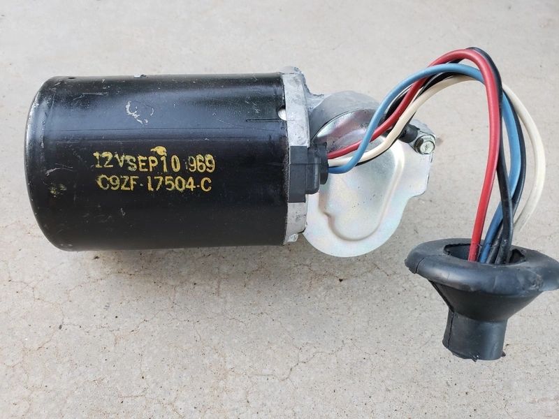 Black electrical motor with colored wires attached.