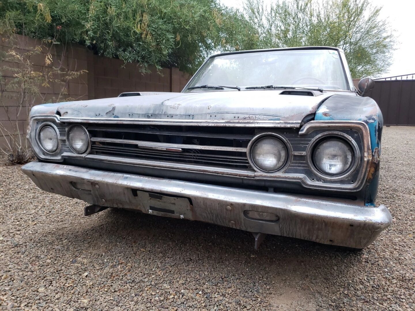 Old rusty car with dual headlights front.