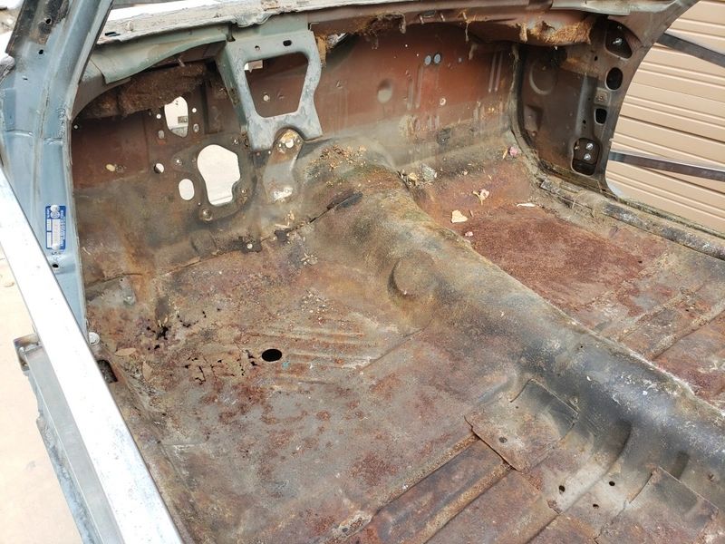 Rusty car interior with exposed metal floor.