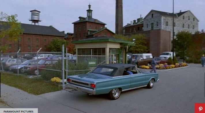 Blue car entering industrial complex entrance.