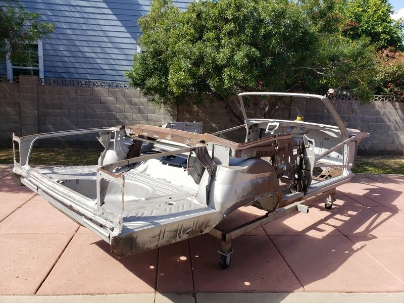 Car frame chassis on outdoor pavement.
