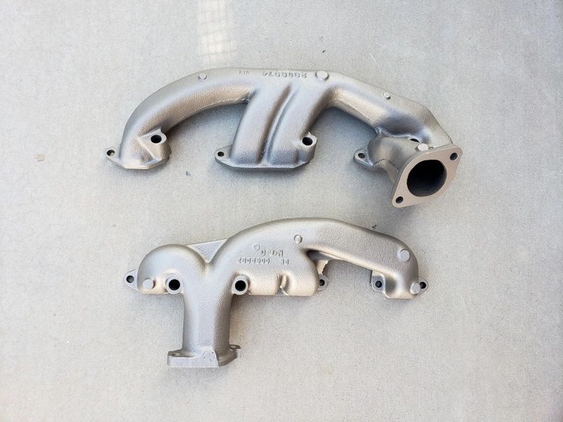 Two metal exhaust manifolds on concrete.