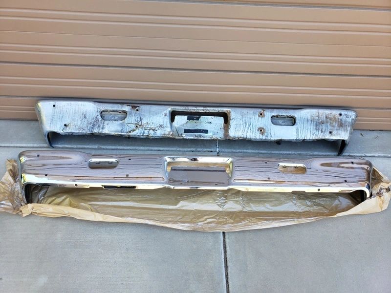 Two old car bumpers on concrete floor.