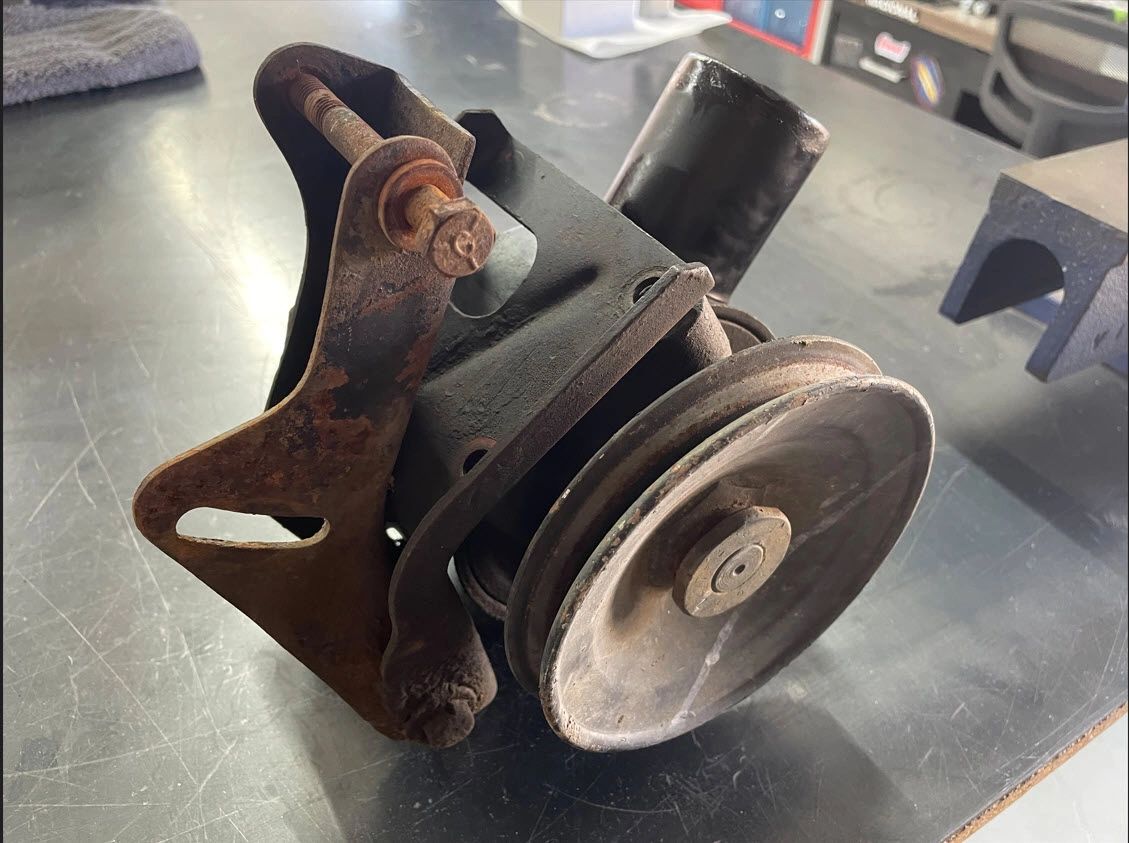 Rusty car engine pulley on a table.