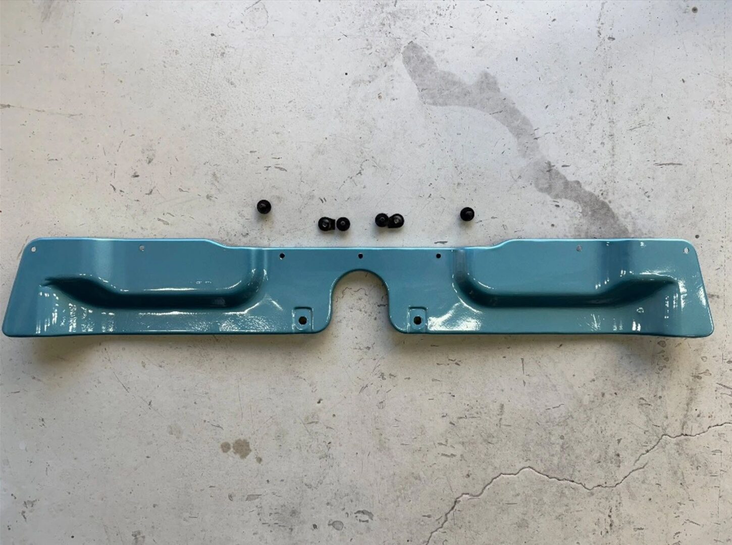 Blue metal car part on concrete floor.