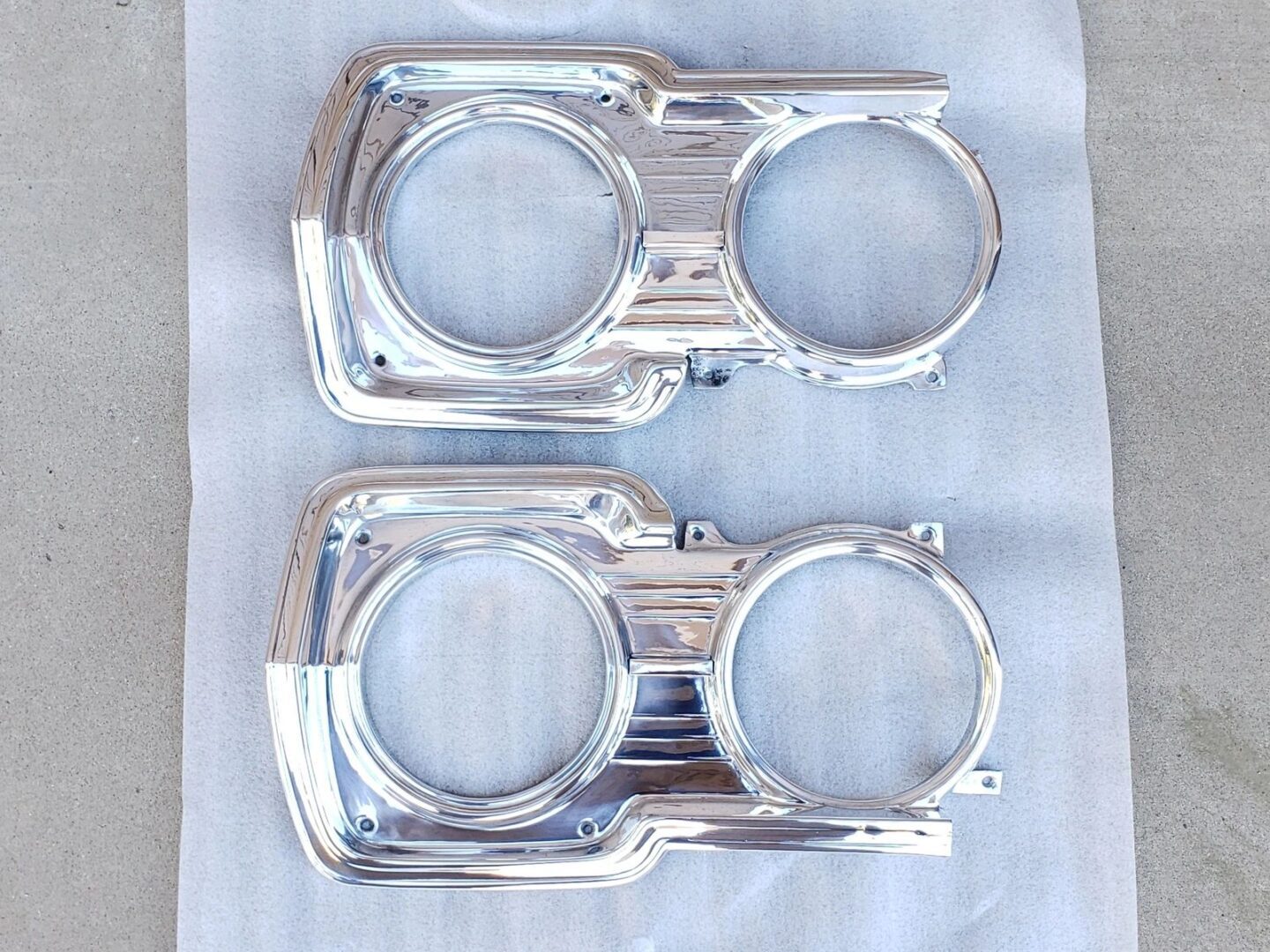 Chrome headlight bezels on white surface.