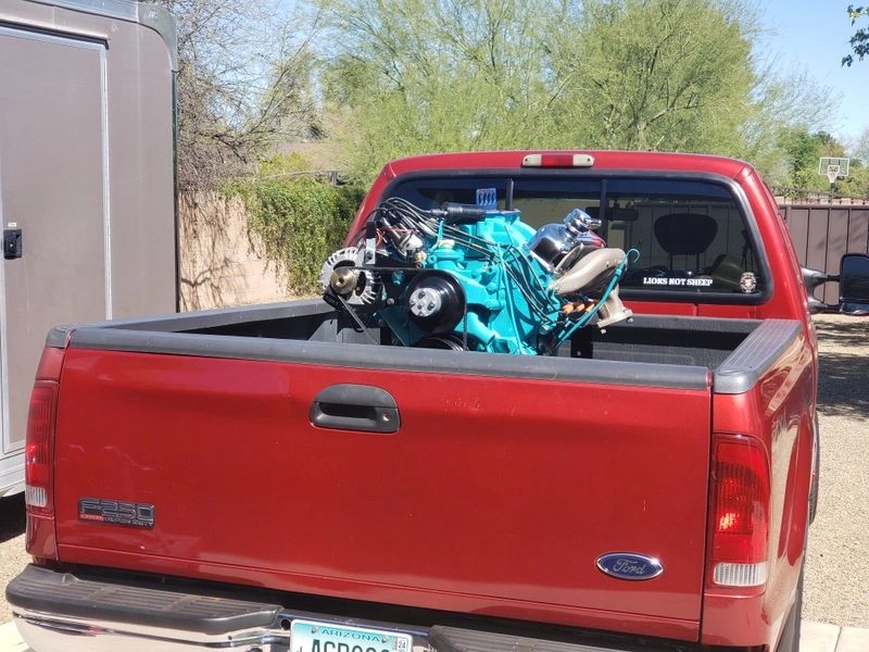 Red truck carrying a blue engine.