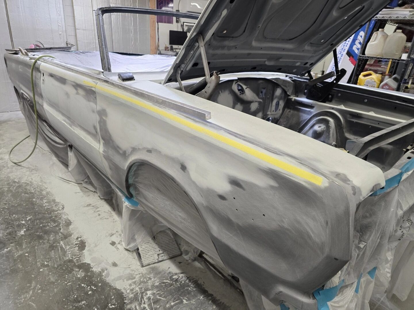 Classic car undergoing restoration in workshop.