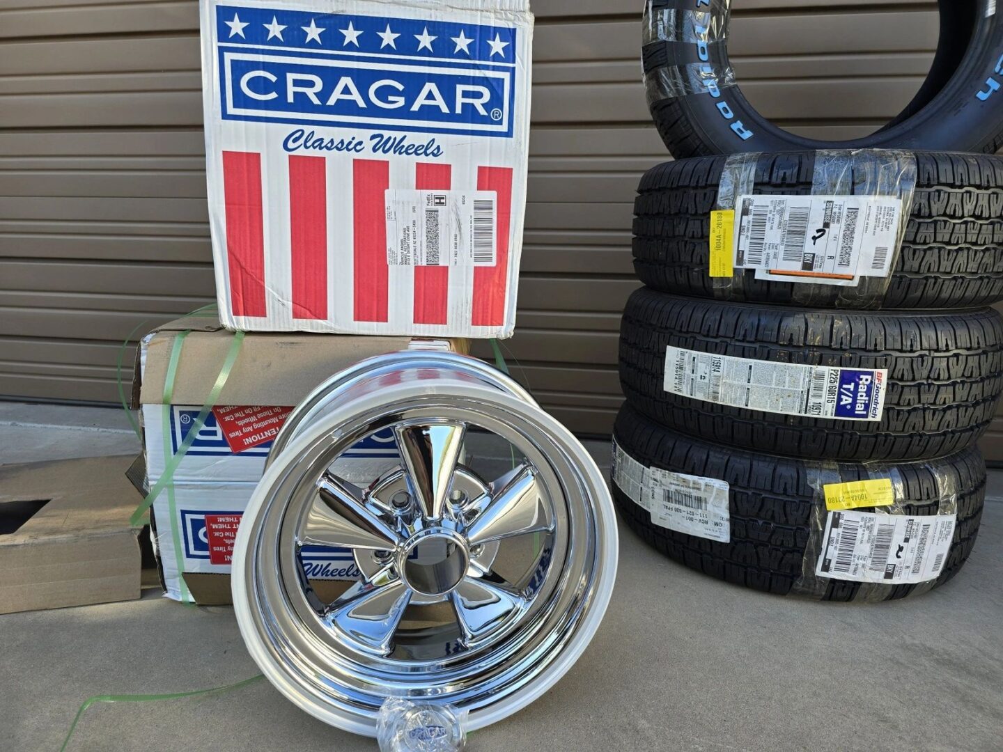 Chrome wheel and stacked tires near boxes.