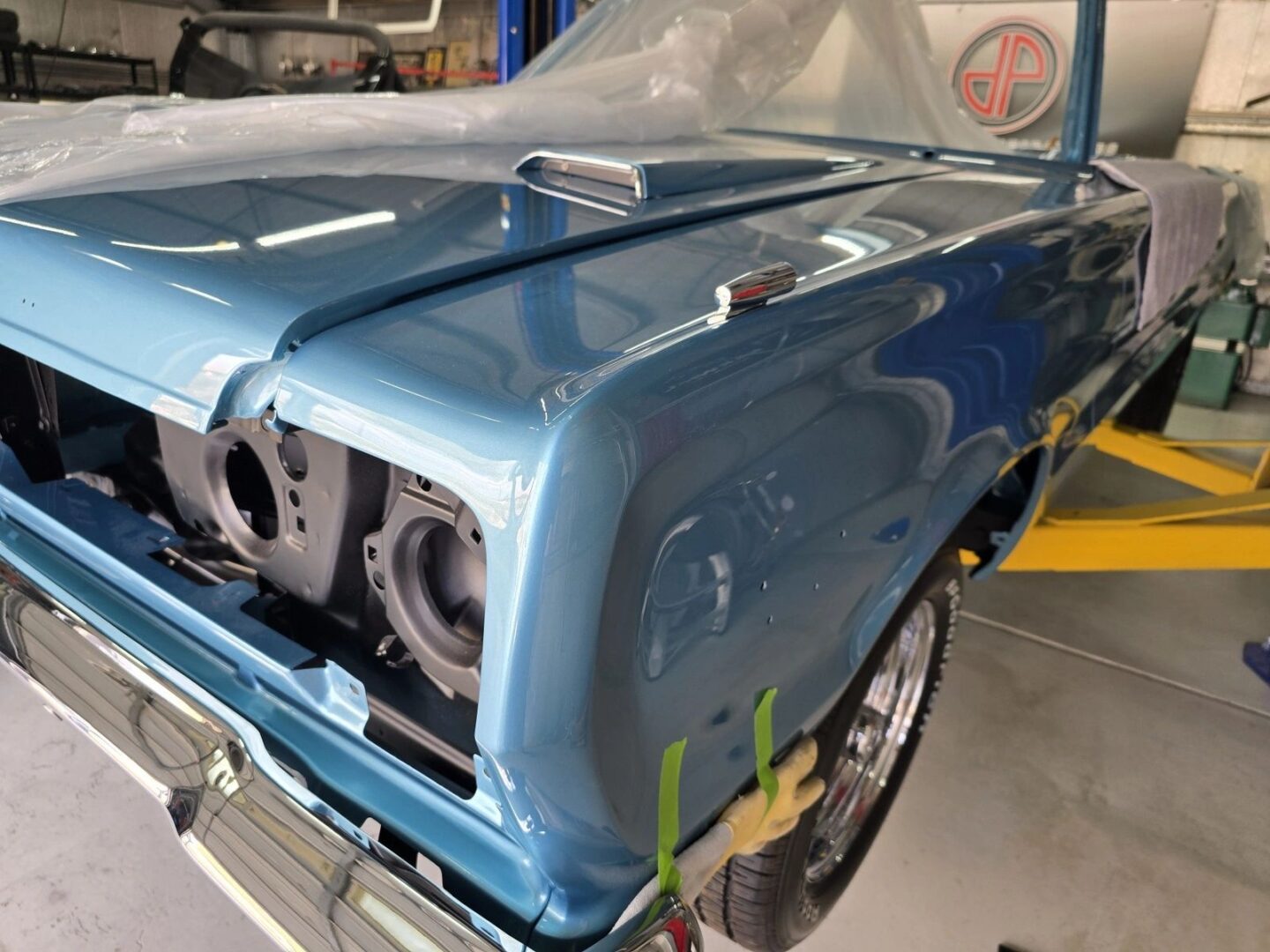 Classic blue car under restoration in garage.
