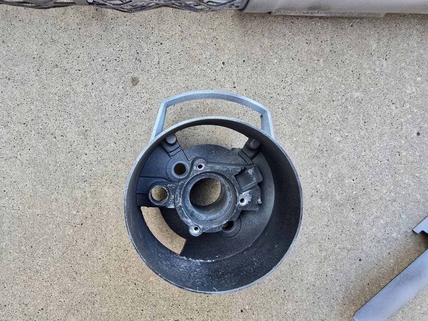 Round metal part on concrete surface.