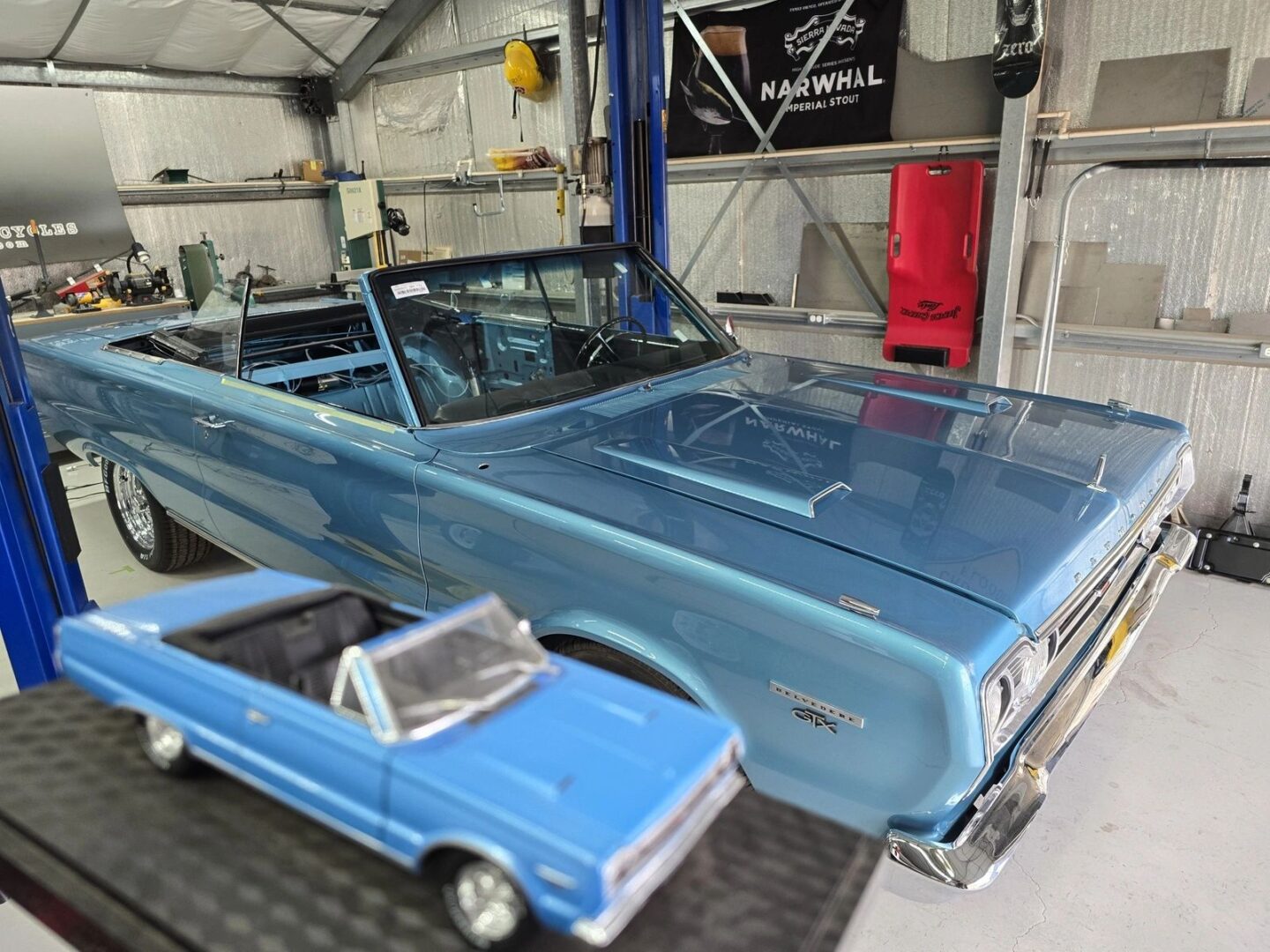 Blue convertible car beside its miniature model.