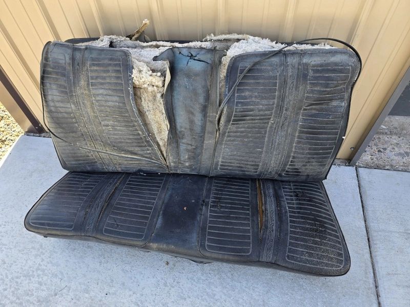 Worn-out car seat on concrete surface.