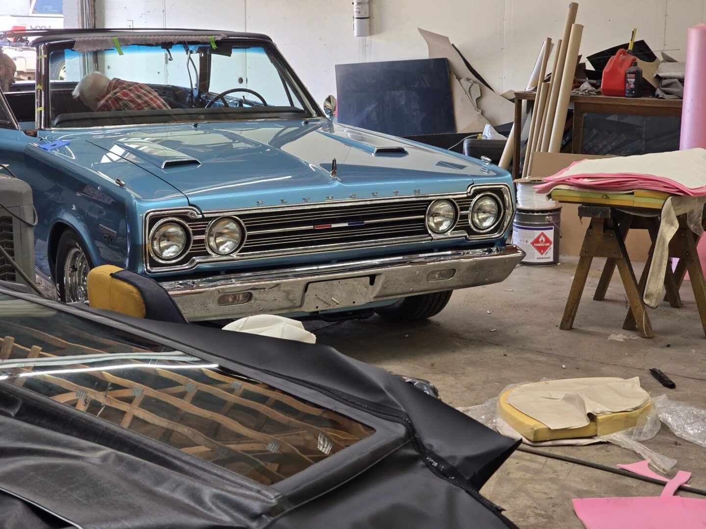 Blue vintage car in cluttered workshop.
