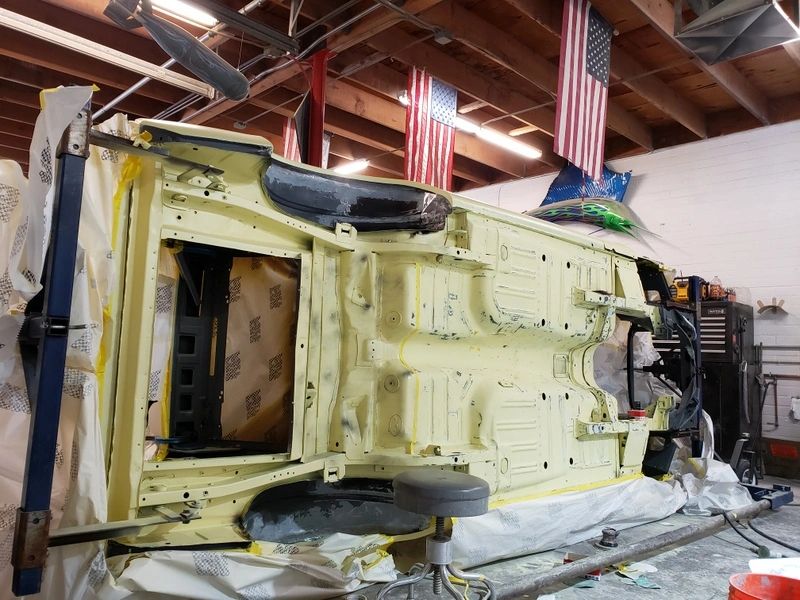 Car undercarriage being restored in workshop.