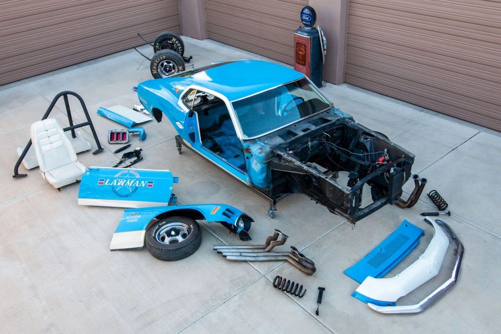 Disassembled blue car with various parts.