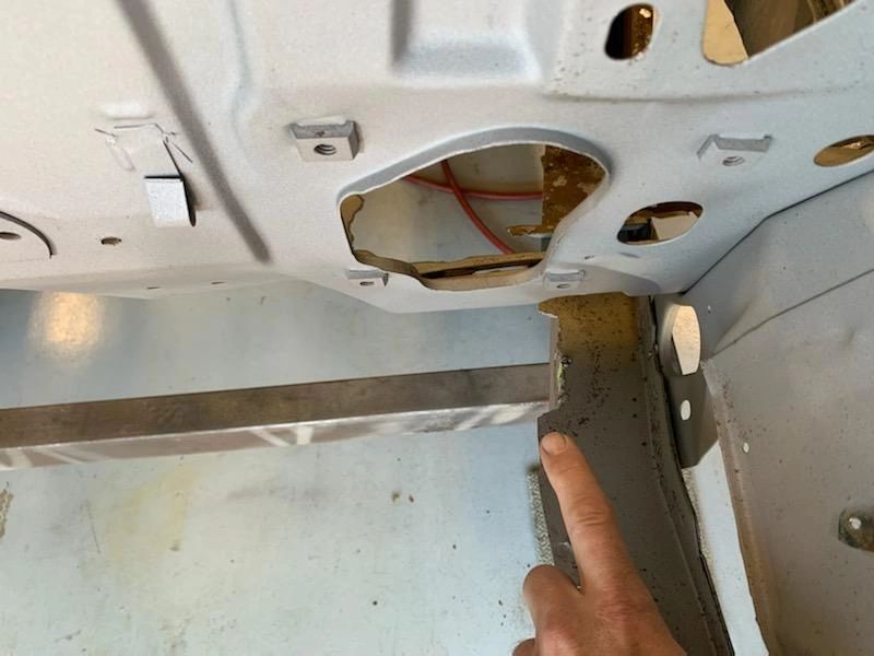 Finger pointing at car trunk repair area.