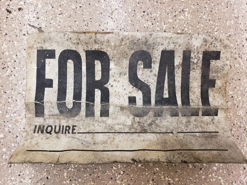 Worn "For Sale" sign on ground.