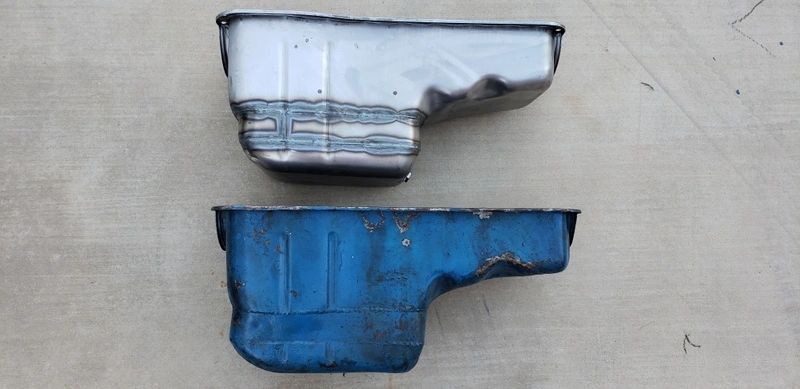 Two metal oil pans on concrete surface.