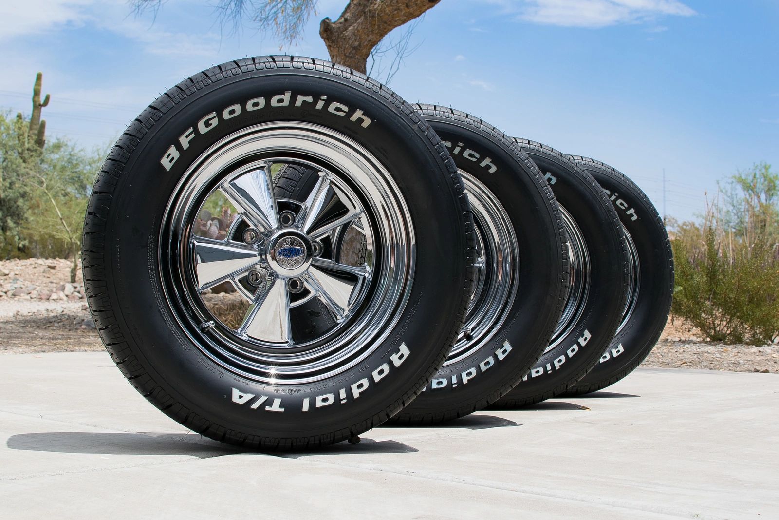 Four car tires stacked outdoors on pavement.