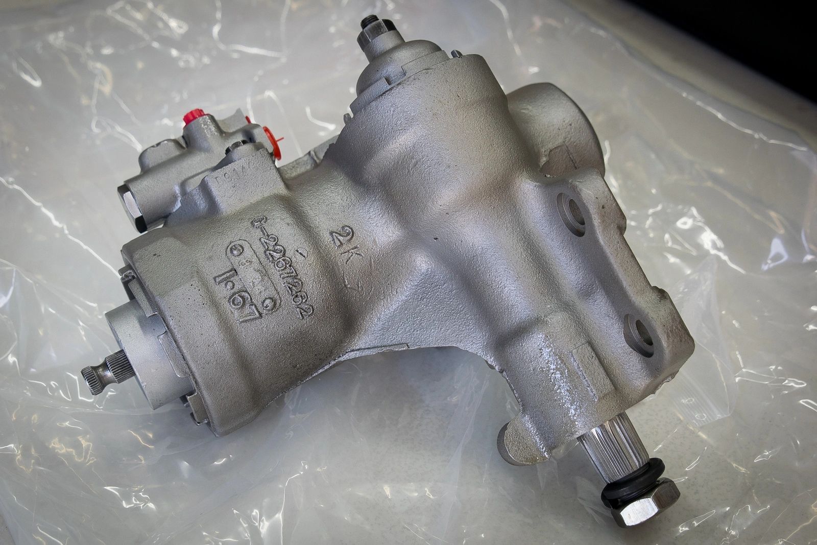 Silver automotive part on a plastic sheet.