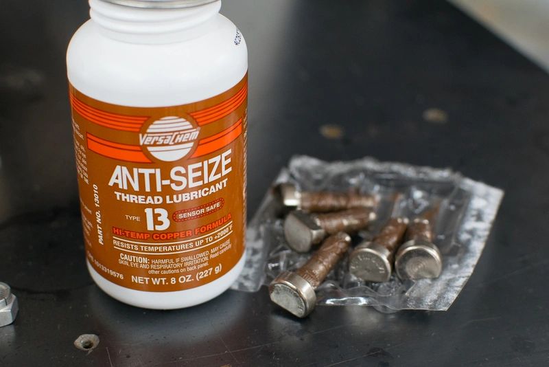 Anti-seize lubricant bottle with bolts nearby.