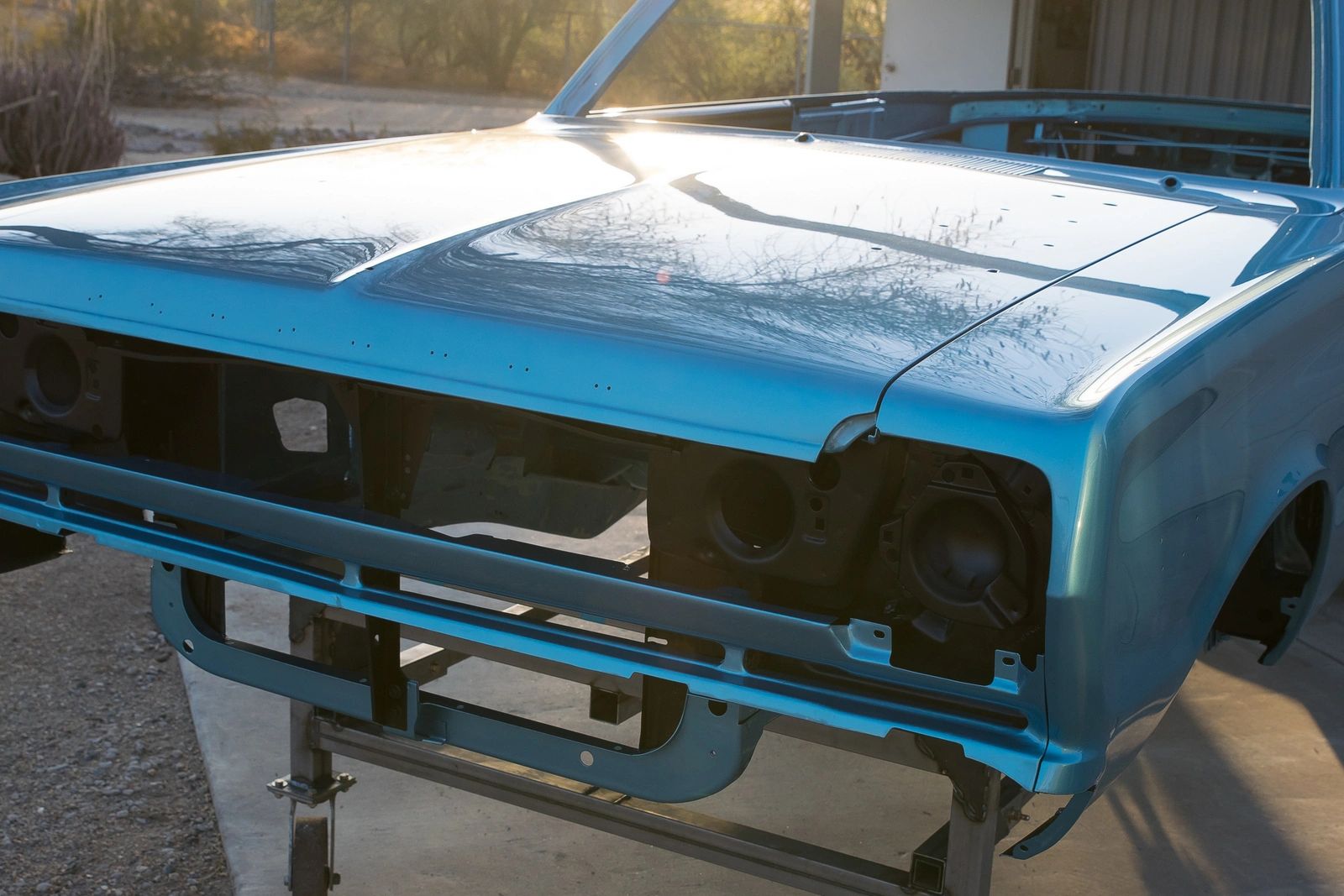 Blue car chassis without front bumper.