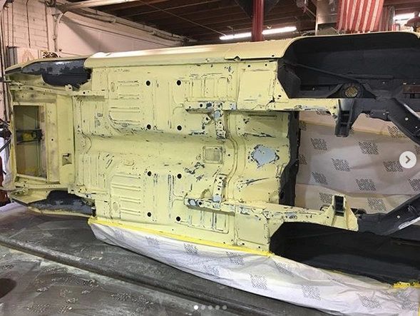 Car chassis undergoing restoration in workshop.