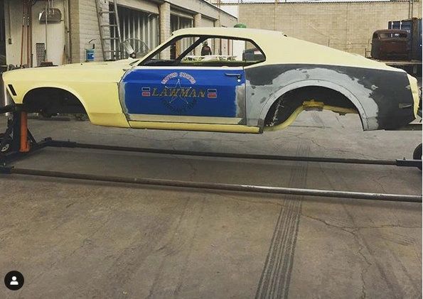 Car body on rotisserie in workshop.