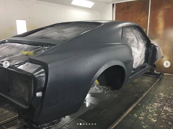 Car undergoing paint preparation in workshop.